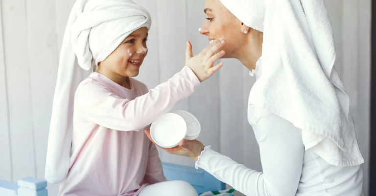 A beautiful baby girl and her mother are applying cream on one each other's face