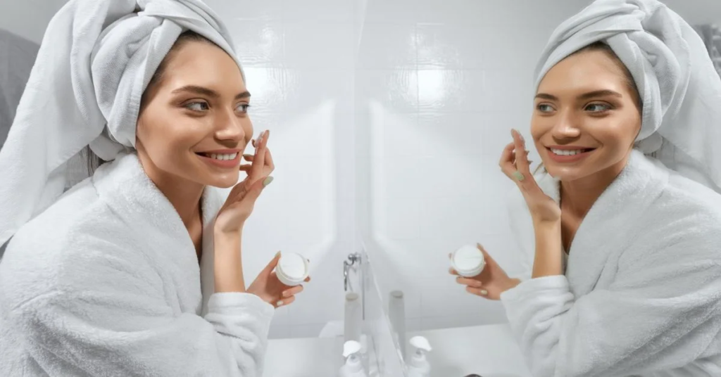 a gorgeous lady iS appyling cream on her face infront of a mirror